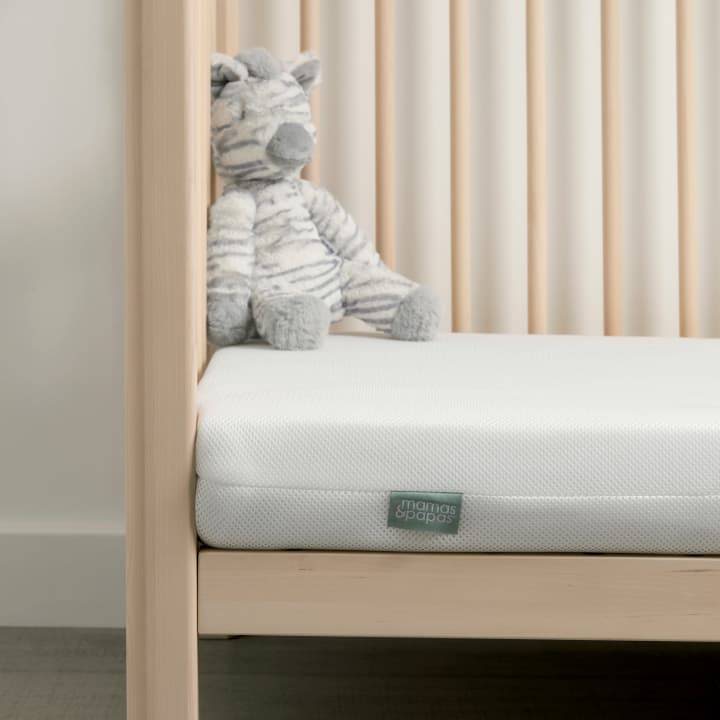 Baby stood in a cot on a mattress