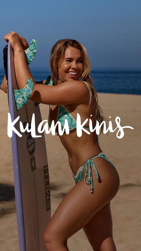 Woman in bikini holding a surfboard on the beach.