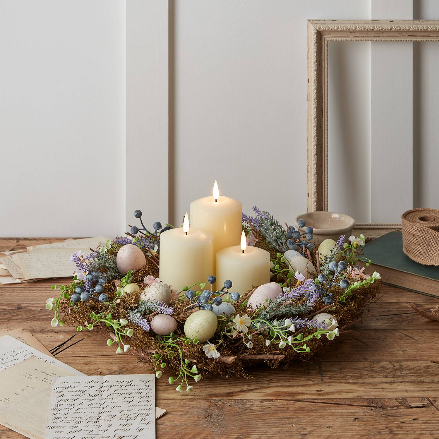 Une Couronne de Mousse Œufs de Pâques et Bougies TruGlow® posée sur une table. 