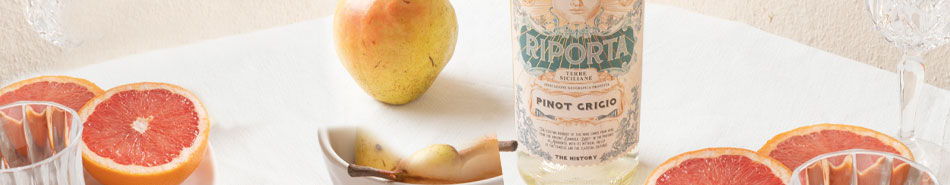 Bottle of beverage surrounded by sliced grapefruit and a pear.