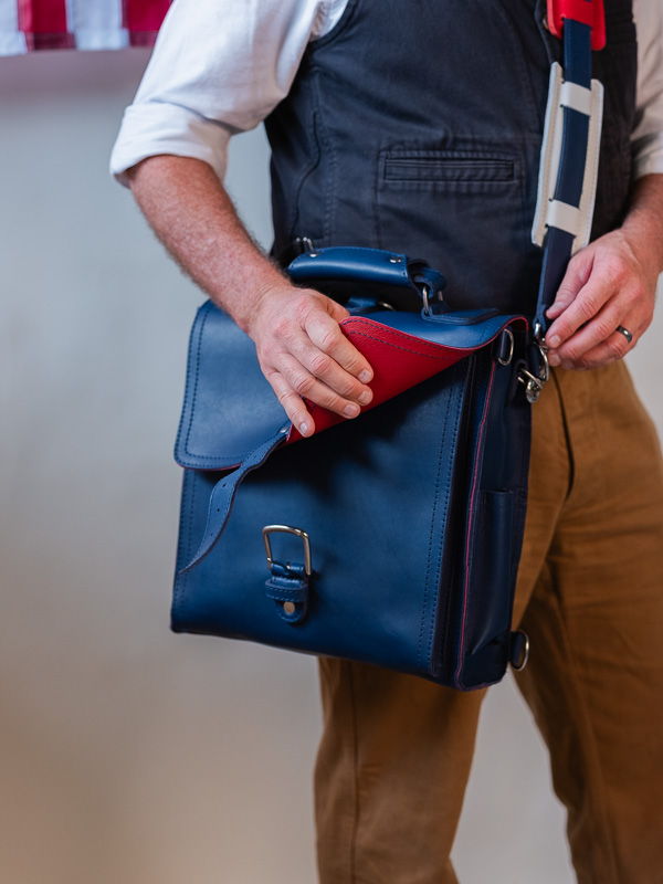 Person holding a blue bag with a red flap.