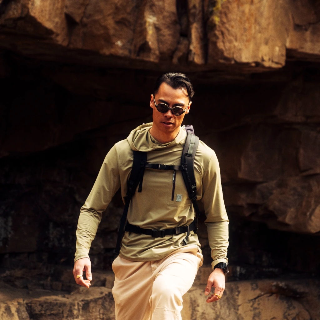 Person hiking in a canyon, wearing sunglasses and a backpack.