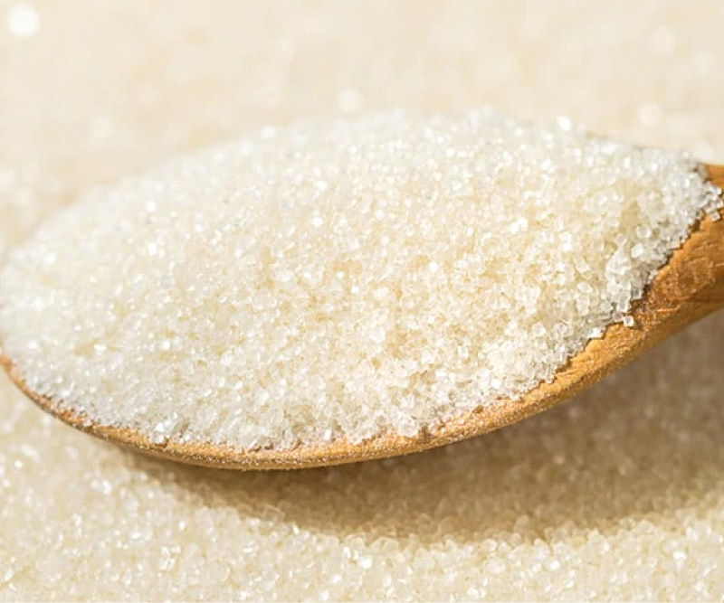 A wooden spoon filled with granulated sugar.