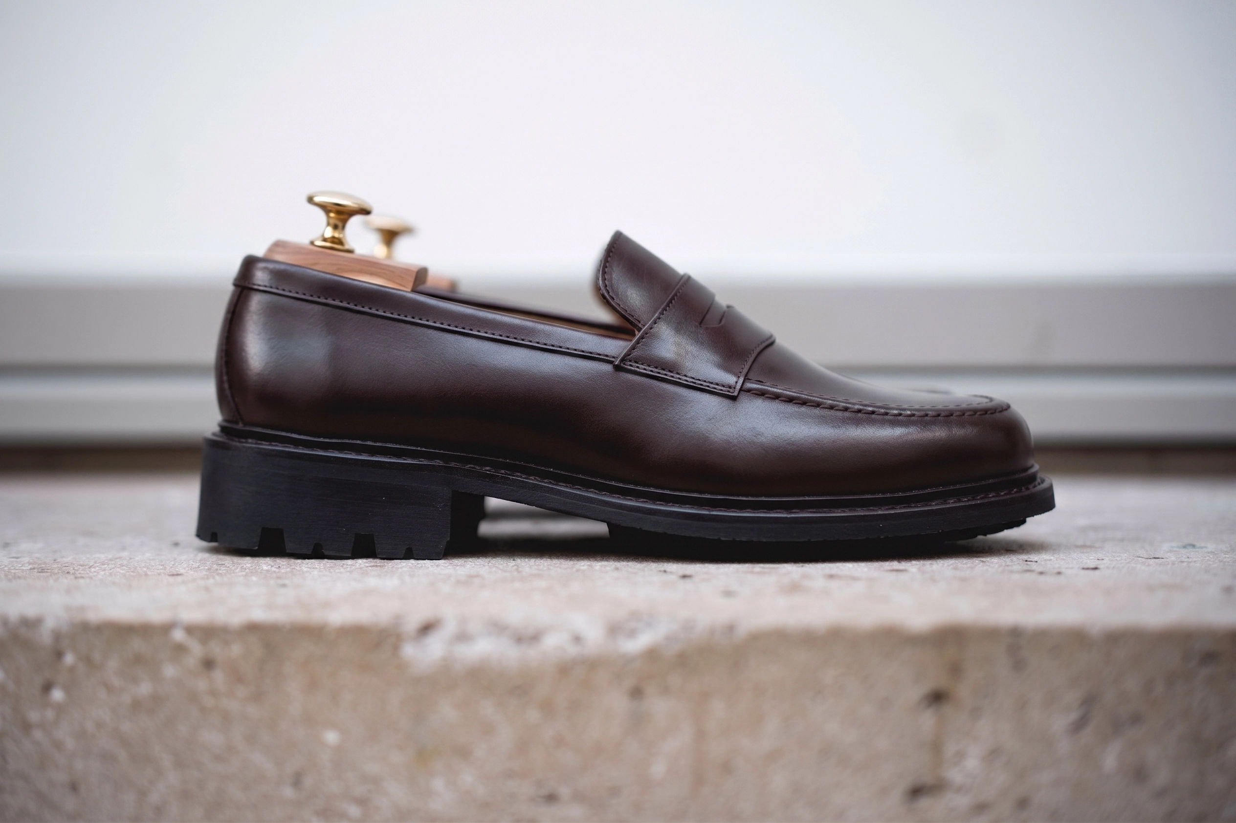 A brown leather loafer shoe displayed on a stone surface.