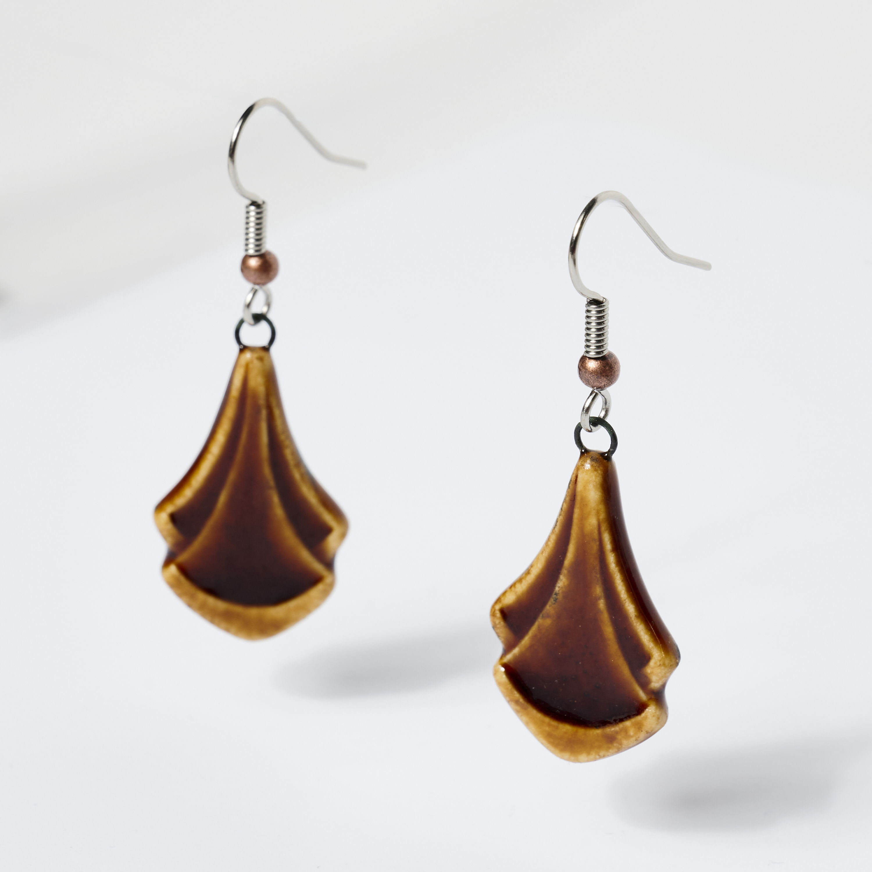 Brown ceramic dangle earrings with a unique leaf-like design.