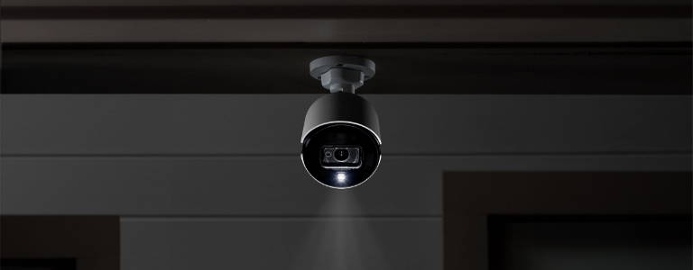 analog security camera on eaves at night with deterrence light