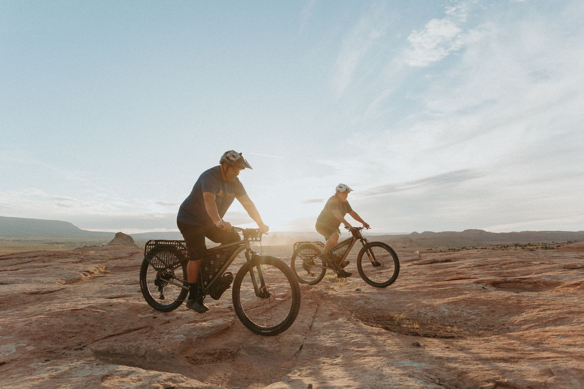 Two cyclists riding bikes on rocky terrain at sunset. Esker Cycles Hayduke LVS in the Navajo Nation