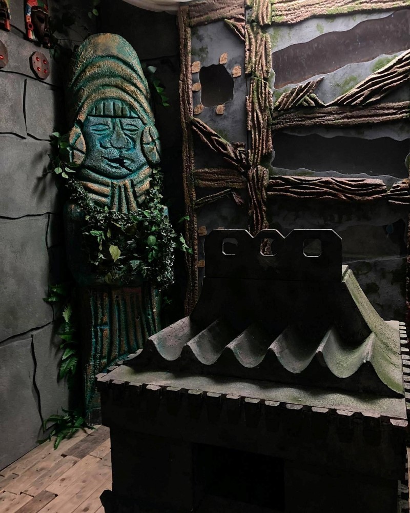 A dimly lit room with a carved statue and decorative wall elements.
