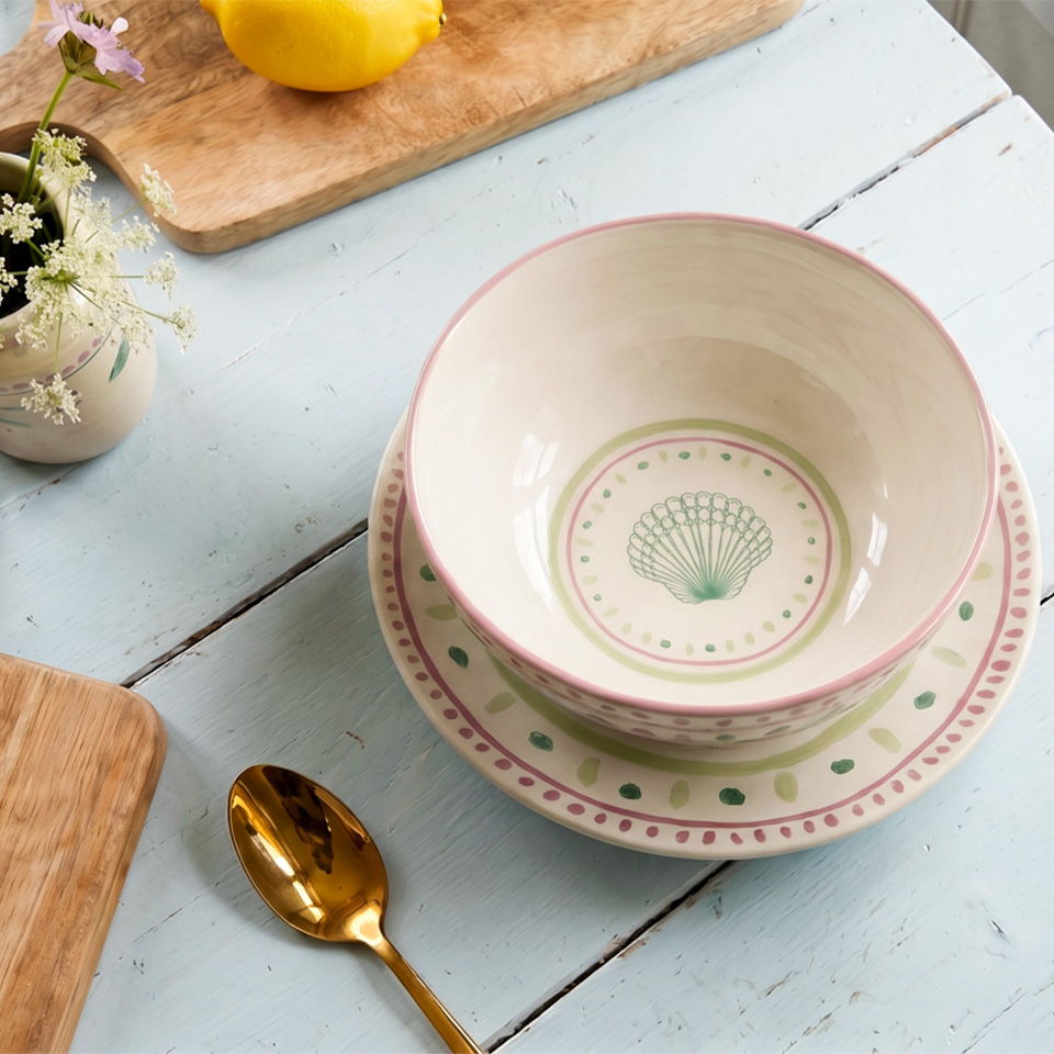 A decorative bowl and plate set on a wooden table with a lemon.