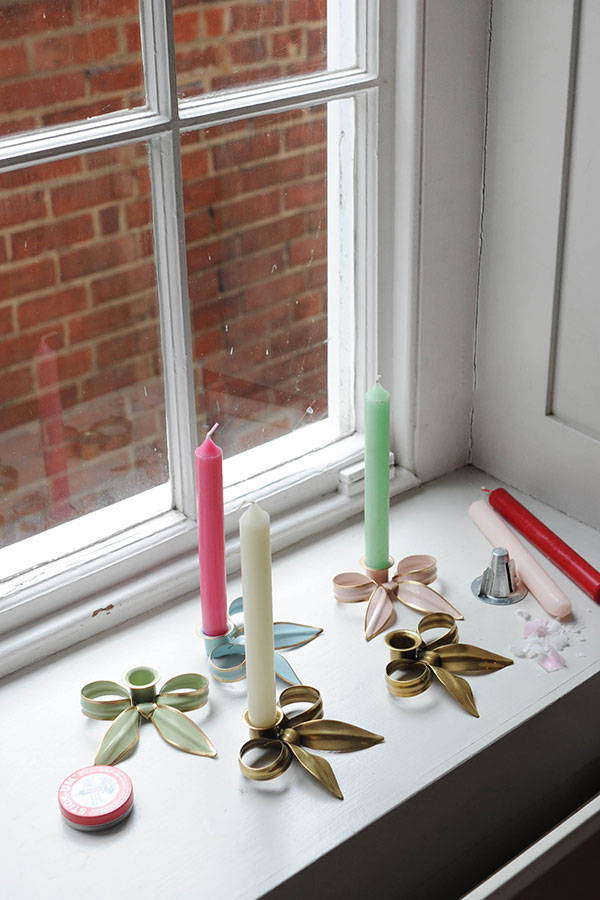 Overhead view of a windowsill filled with Tooka bow candle holders in different colours in the process of being filled with coloured candles.