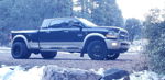 Side profile of two-tone black and tan Ram 3500 dually in snowy forest with rocks in foreground