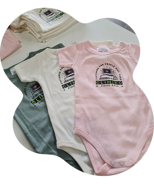 Pink, cream, and sage green Cliniko baby onesies and t-shirts printed with the 