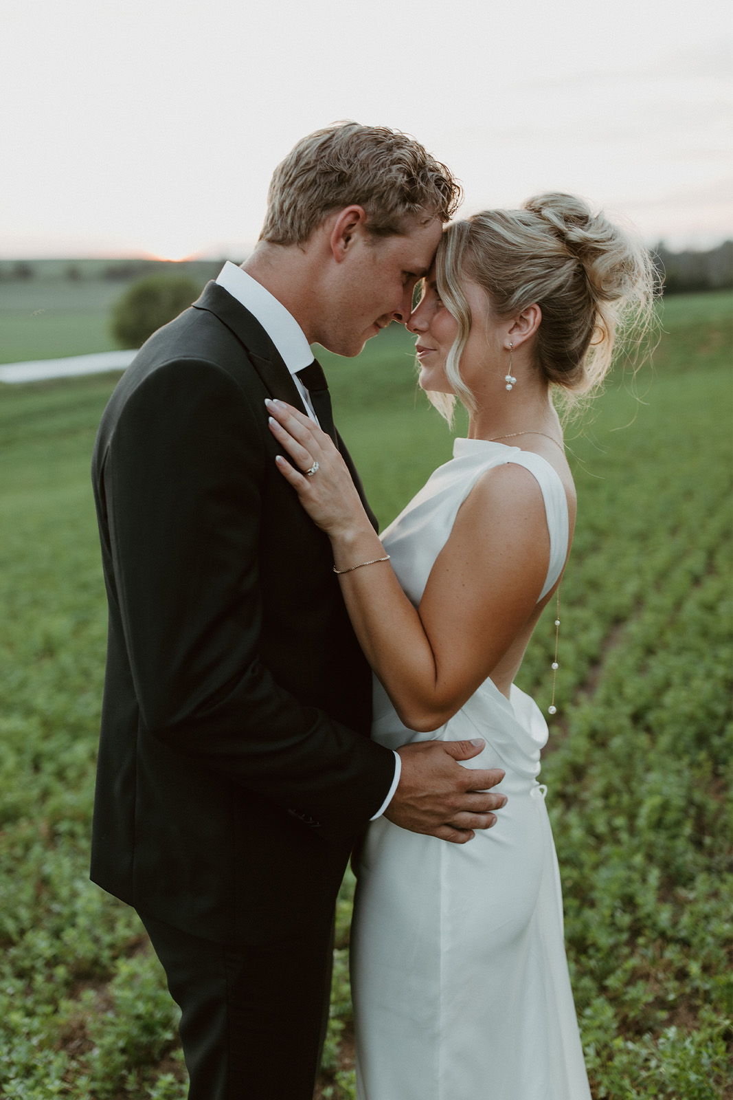 Couple embracing in a field during sunset, showcasing love and intimacy.