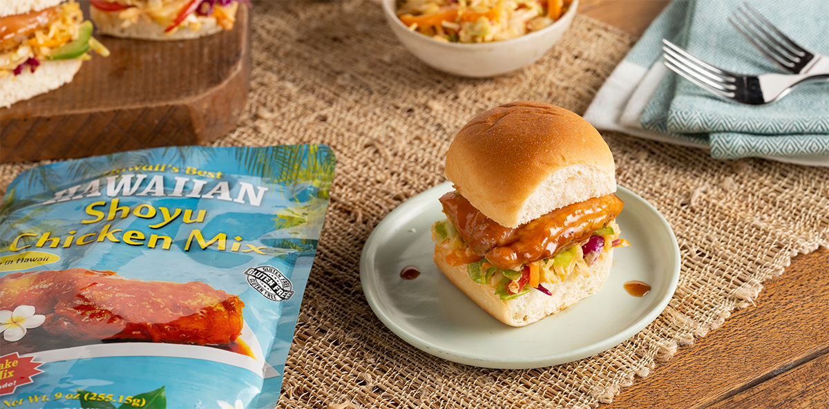 A plate with a slider sandwich and a bag of chicken mix.