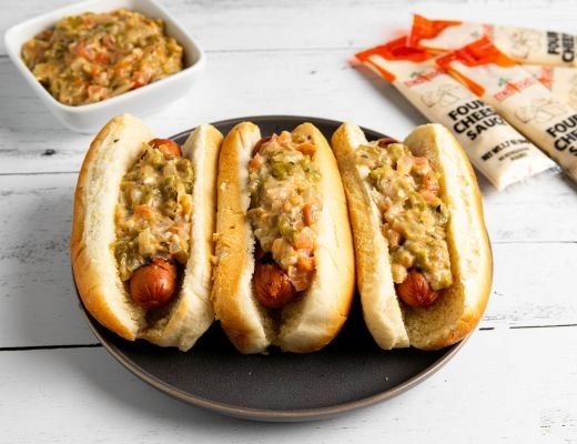 Three hot dogs topped with a savory mixture, served on a plate.