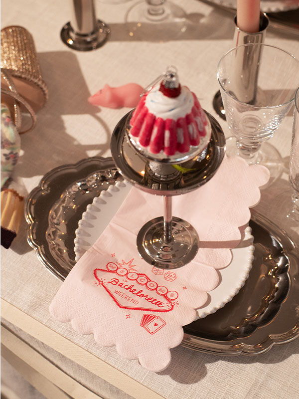 Dessert display with a pink napkin, silver tray, and decorative cupcake.