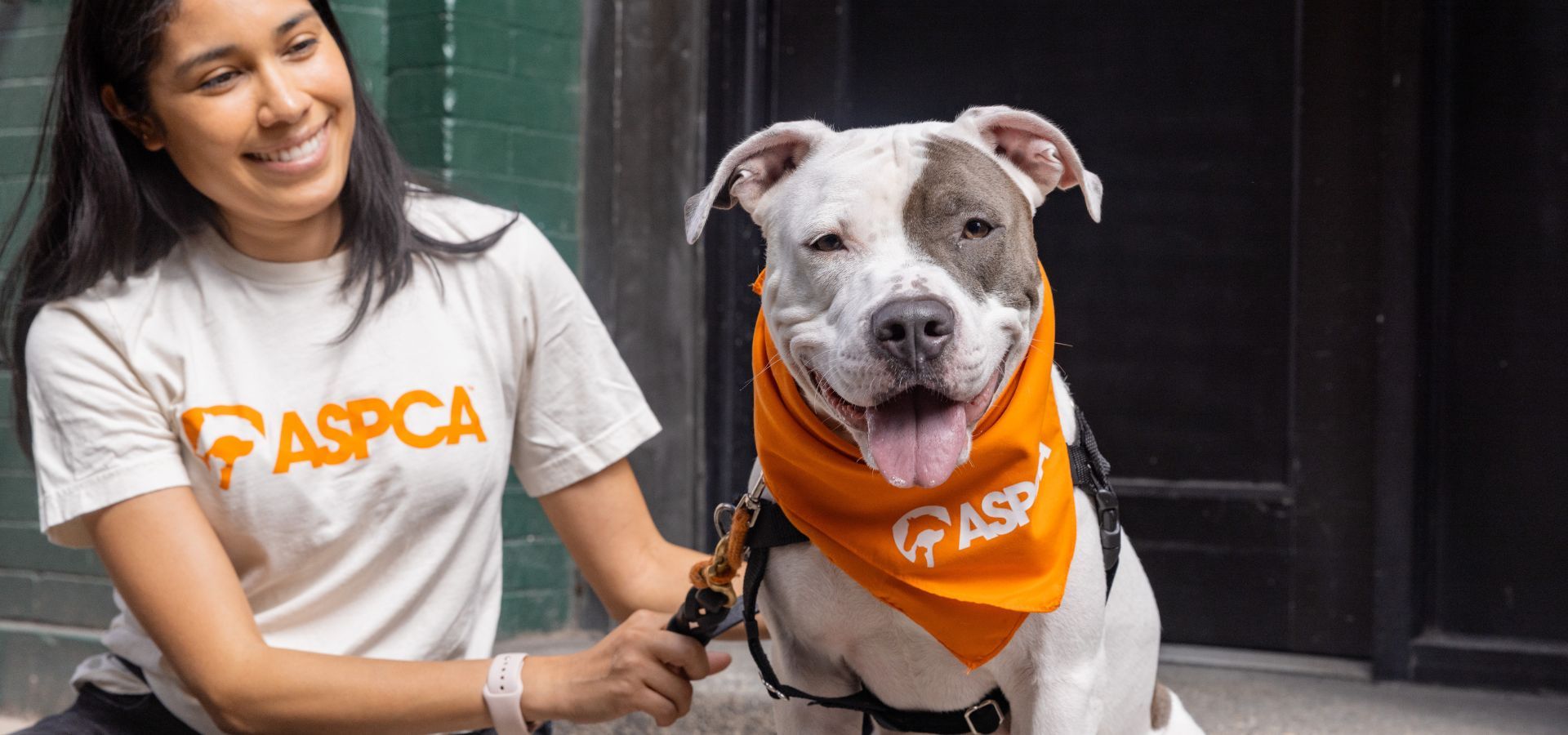 Woman smiling with a dog wearing an ASPCA bandana.