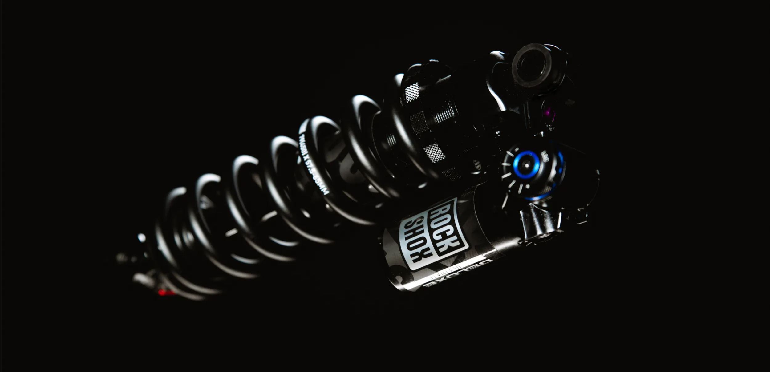 the rockshox super deluxe ultimate coil rear mountain bike shock floating on a black background