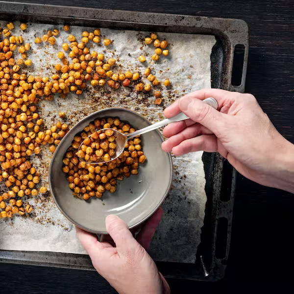 Hands spooning crispy chickpeas into a bowl