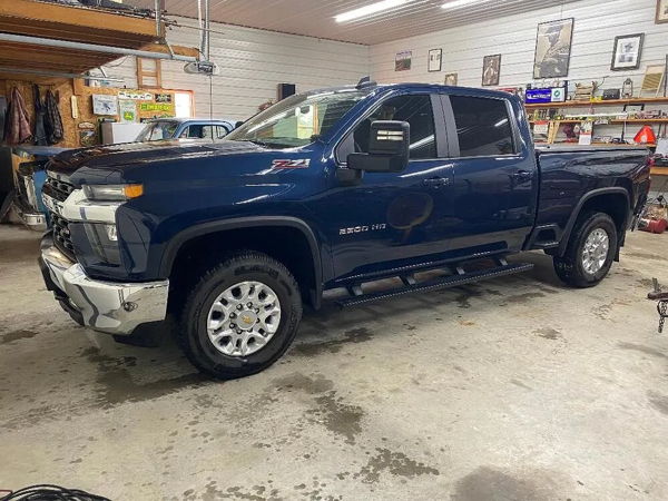 Front side view of Edward's dark blue 2022 Chevy 2500 parked inside a garage with the Mother Trucker 127H air horn install photo 1