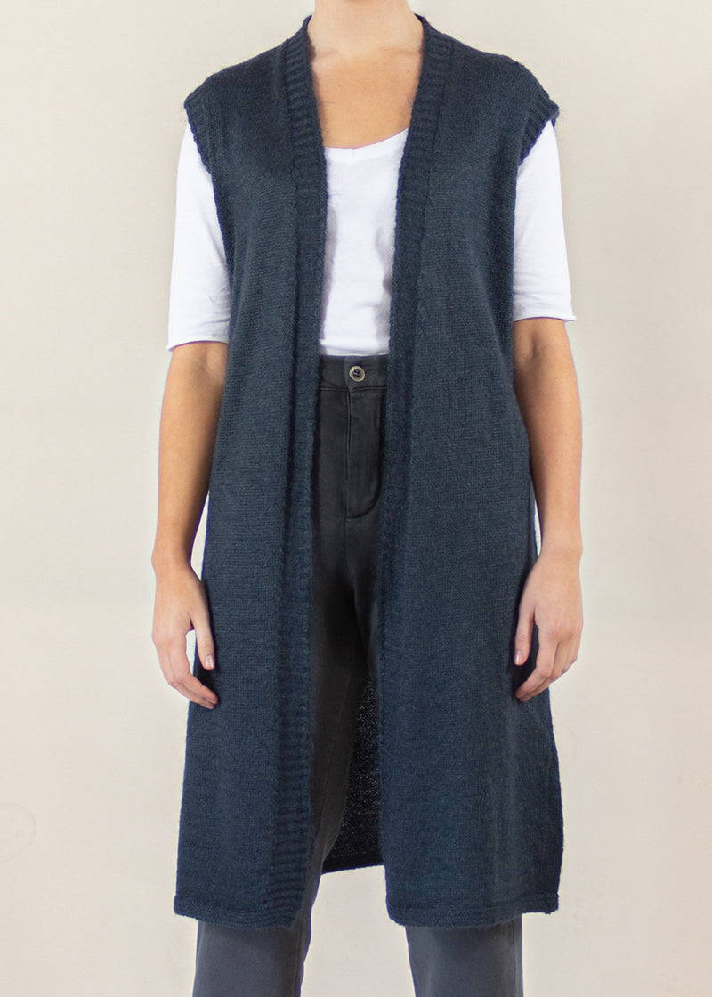A model wearing a dark grey sleeveless, knee length cardigan in a mohair blend
