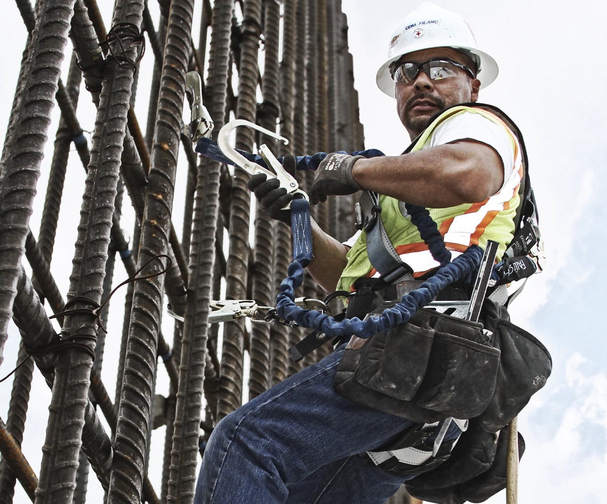 Construction worker climbing rebar attached with a Standard Internal Energy Absorbing lanyard