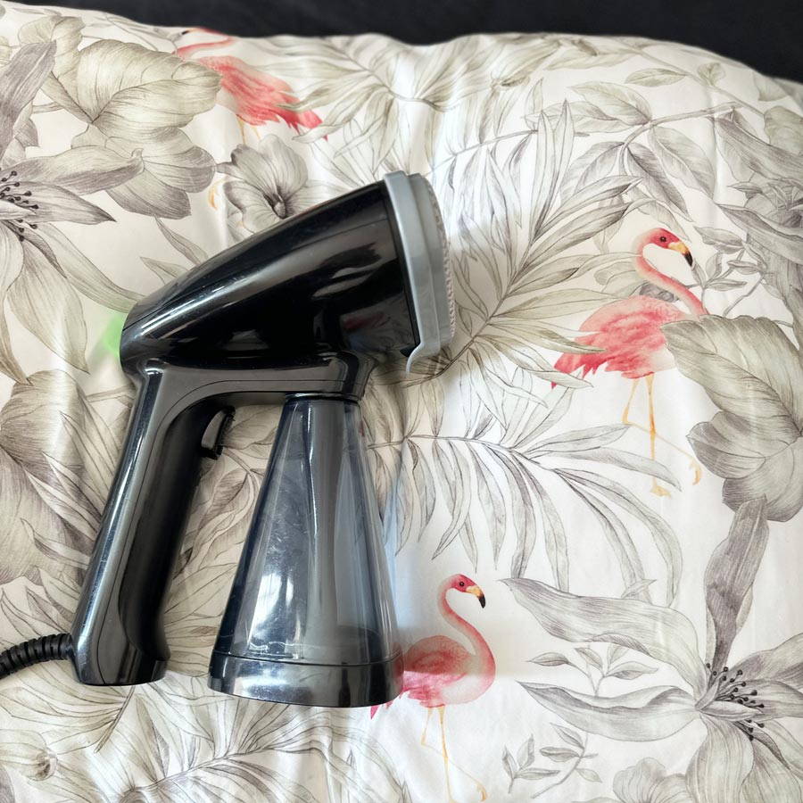 handheld garment steamer on silk bedding 