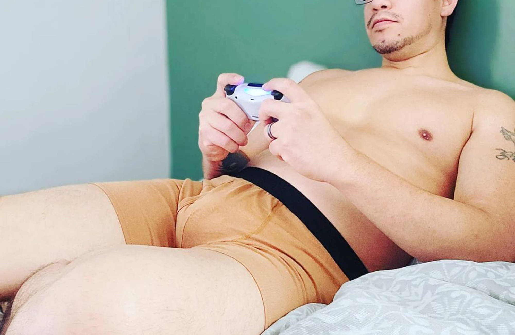 man in glasses wearing only nude boxer briefs playing a video game