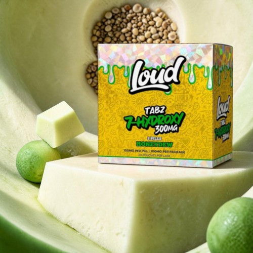 Box of Loud flavored candy surrounded by green fruit and seeds.