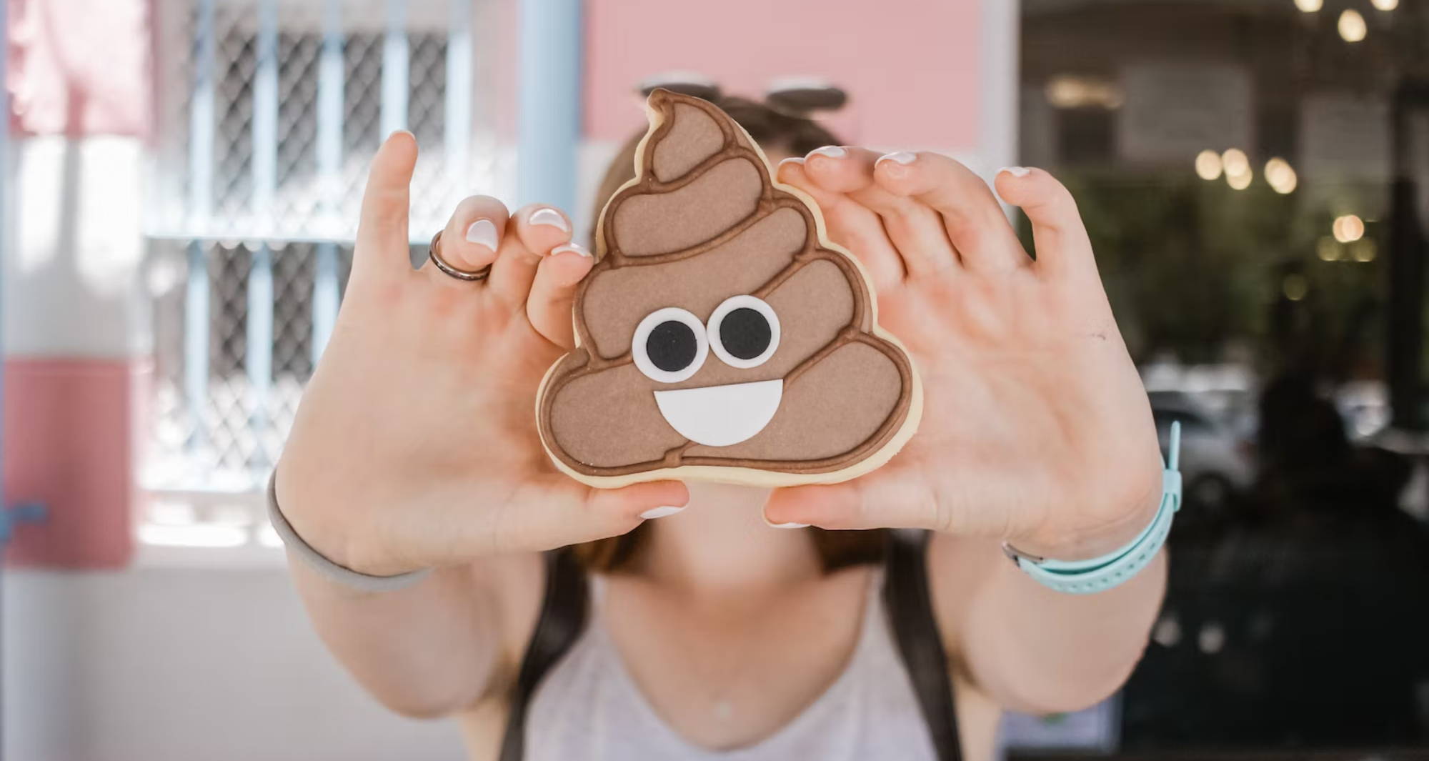 a person holding a cookie of the poop emoji