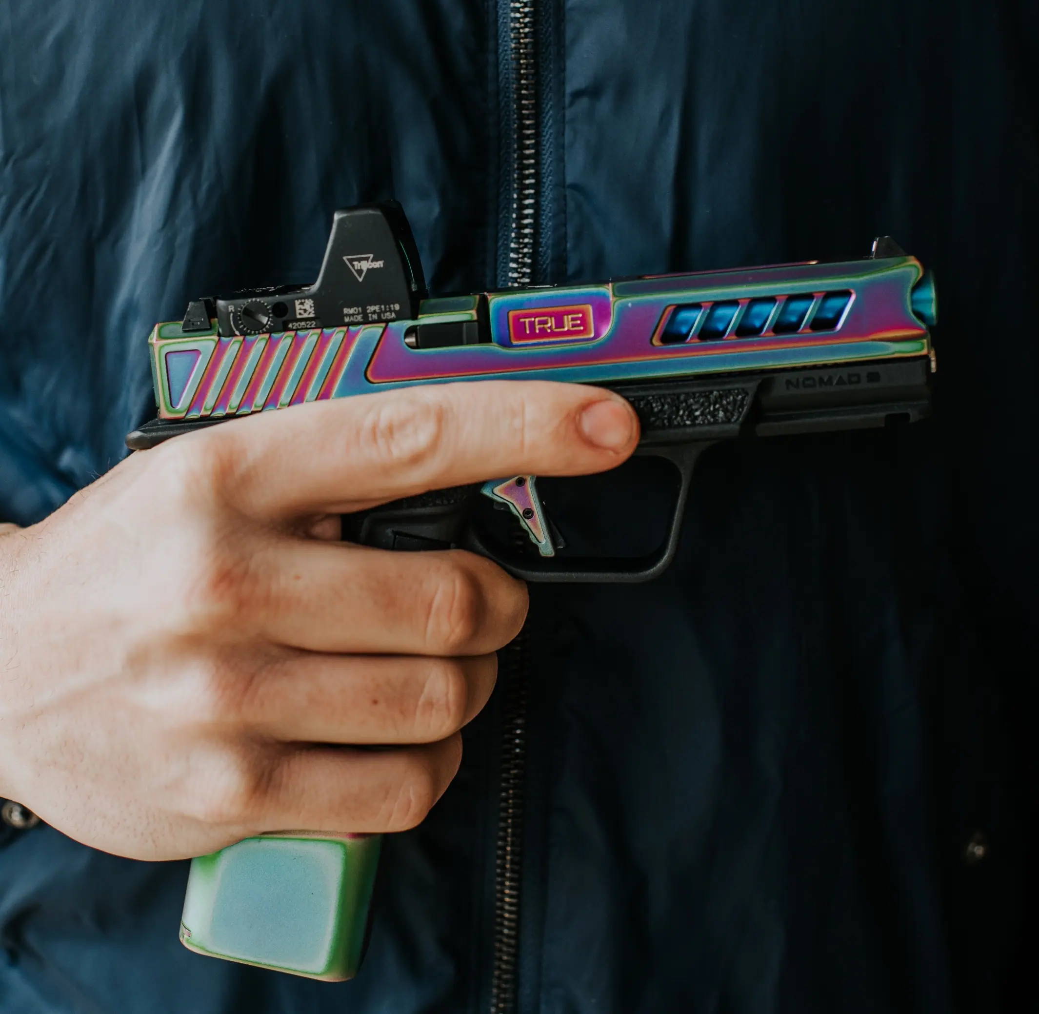 Glock 19, with Spectrum slide barrel and trigger being held by someone in a zip up jacket.
