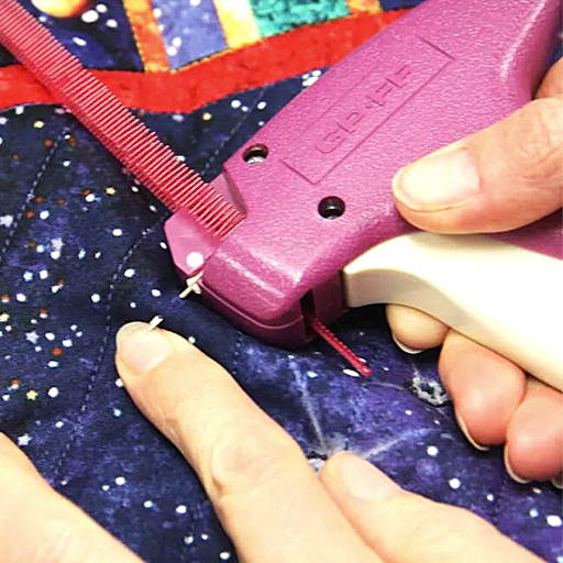 basting quilt layers together using a pink tack gun and little red plastic tacks