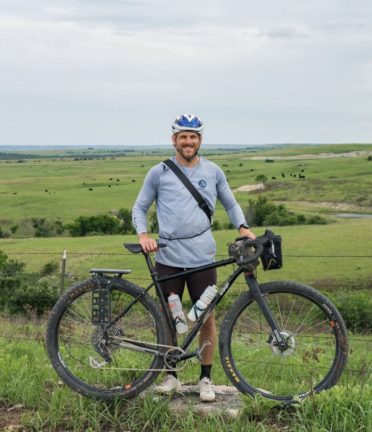 Person standing next to a bicycle in a green landscape.