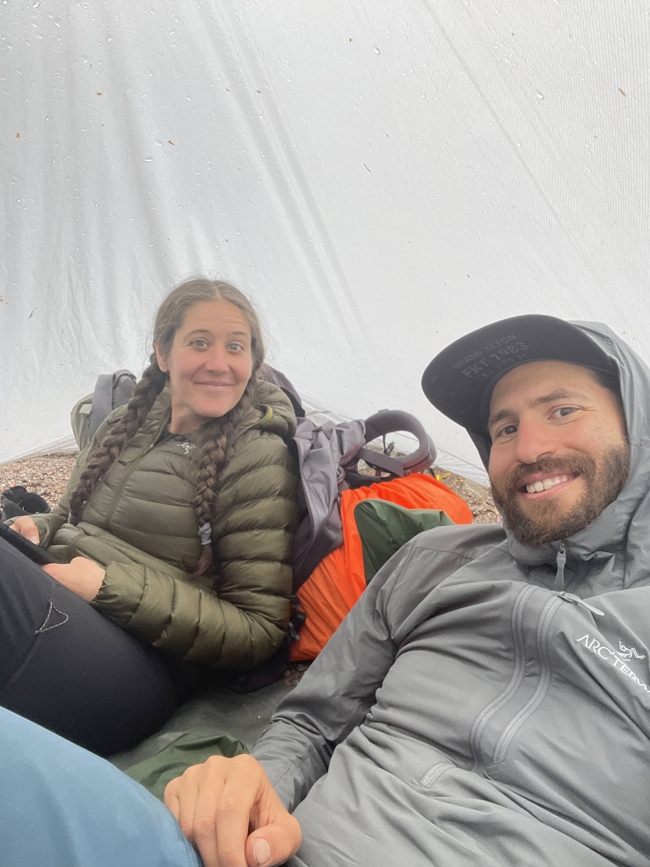 the founders sitting under a tarp waiting out the rain,. our toughest phone cases helped out on this trip.