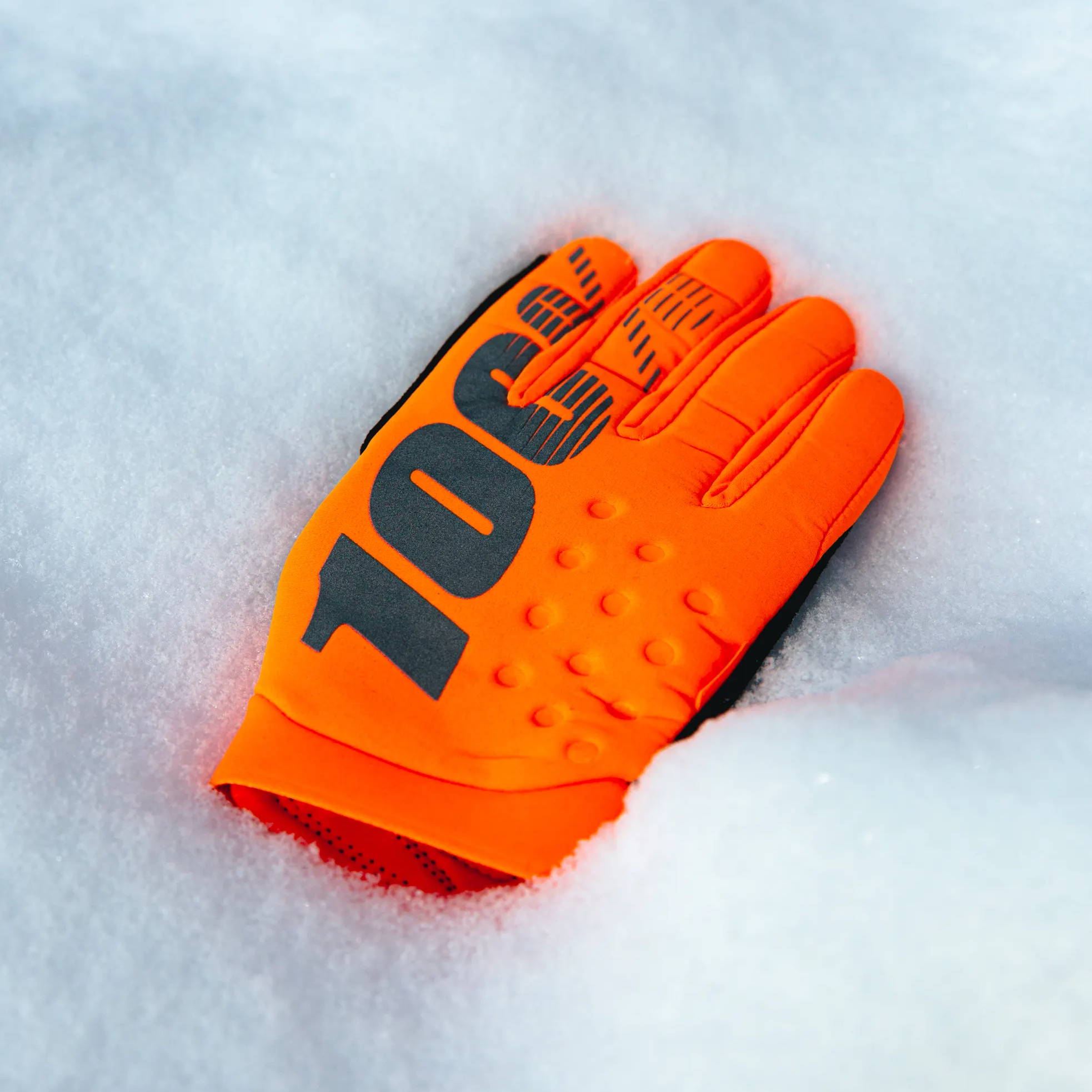 orange 100% brisker mtb gloves on snow