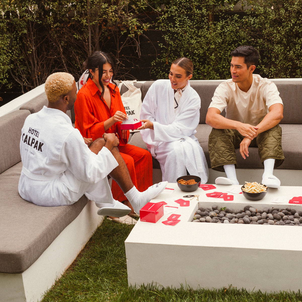 A group of friends playing a card game surrounded by the hotel CALPAK collection.