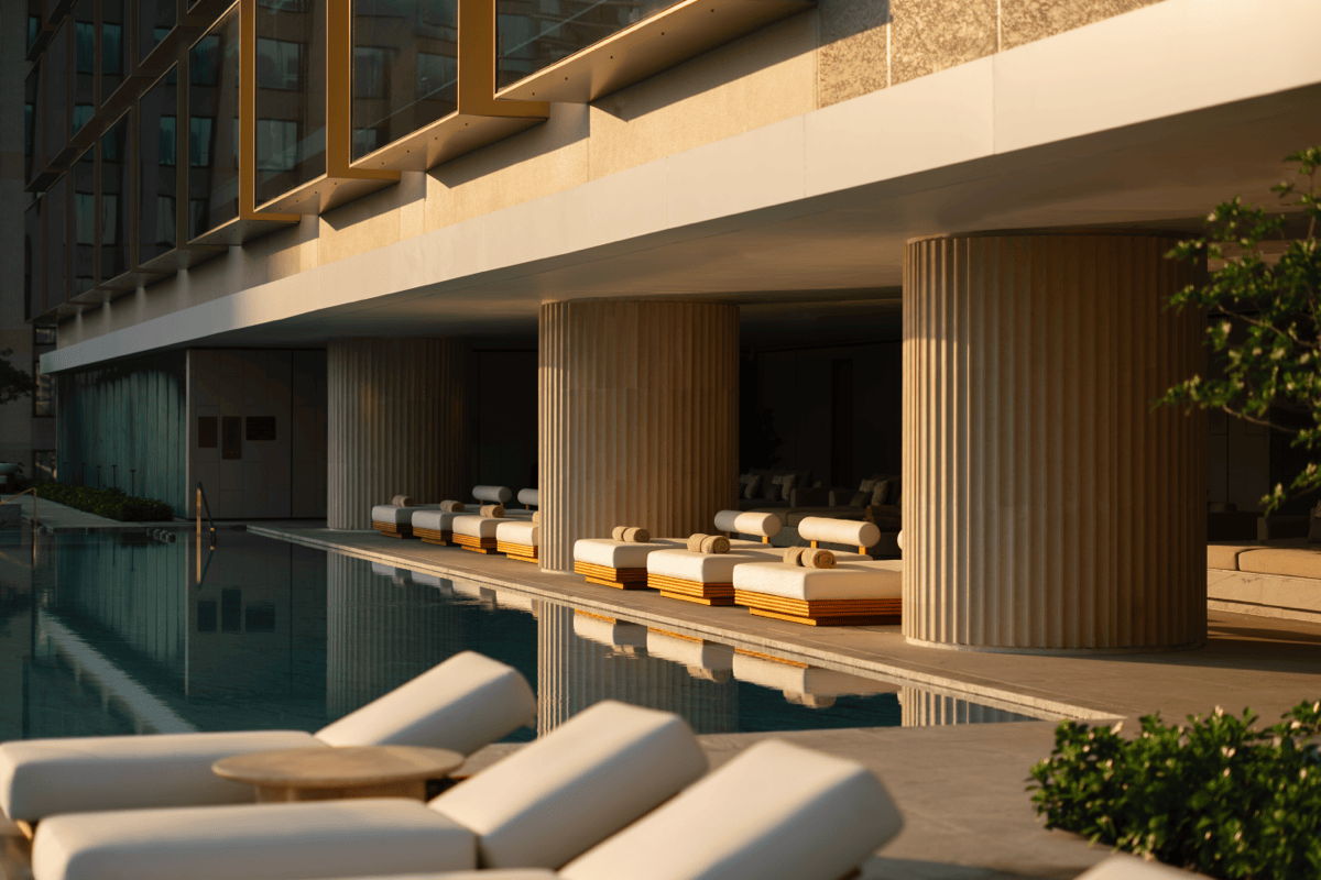Luxury poolside lounge chairs with neutral cushions arranged beside a modern hotel pool, showing high-end outdoor furniture in a hospitality setting.