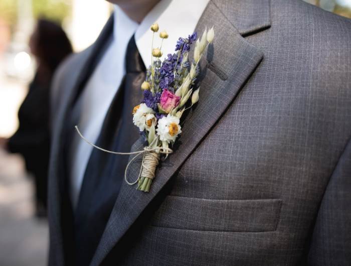 Groom wearing a black tie, gray suit and colorful flower boutonnieres