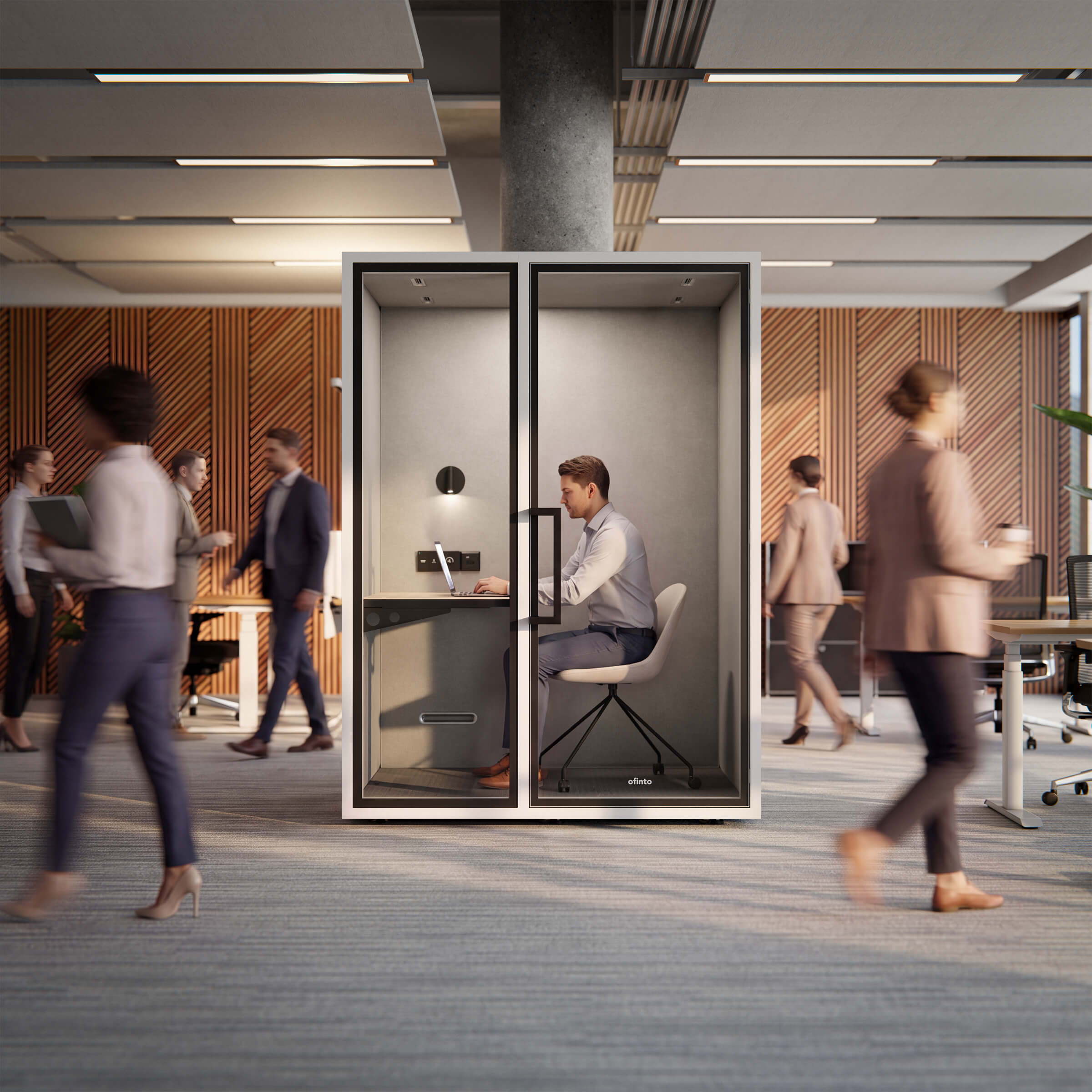 A man works intently on his laptop in the ofinto Focus Work phone booth while colleagues walk by in the open-plan office