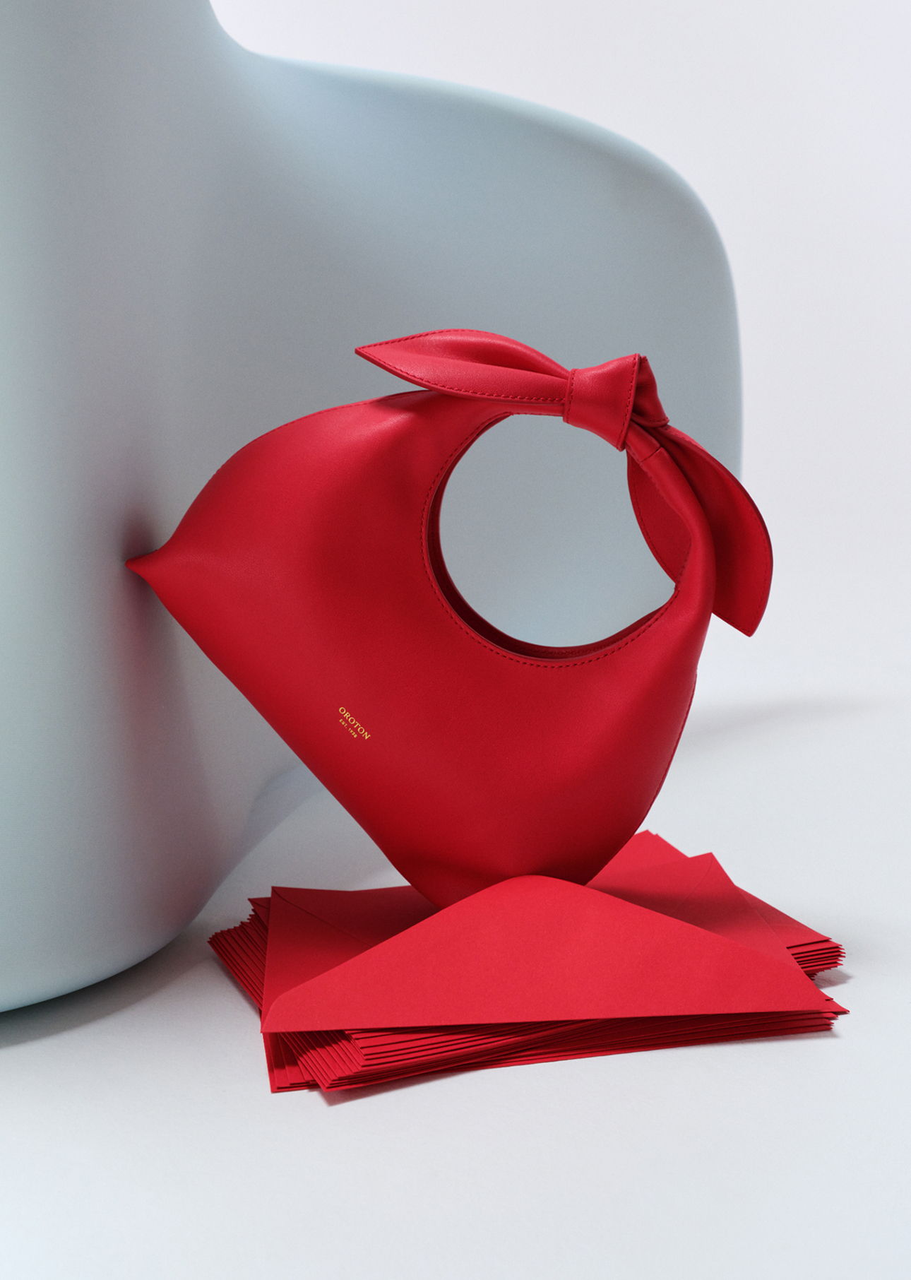 Red fabric with a hole, tied with a knot, near red envelopes.