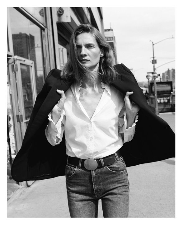 A woman in a black jacket and white shirt standing outdoors.
