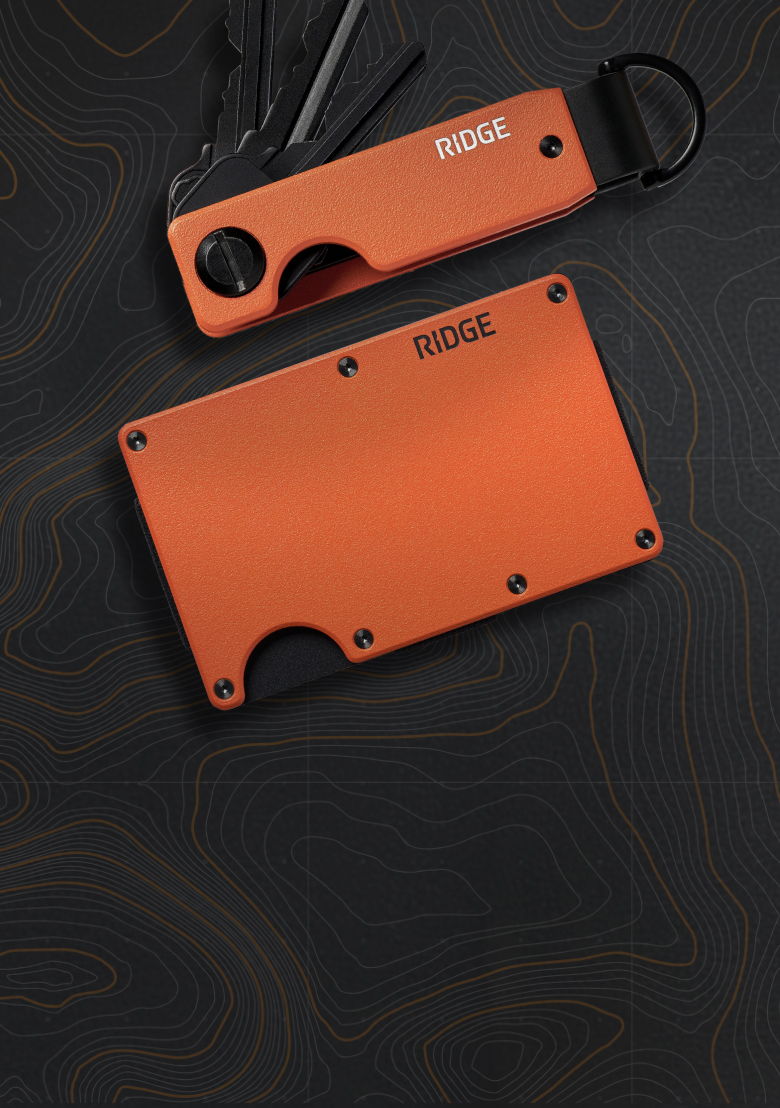 Two orange Ridge wallets on a dark patterned background.