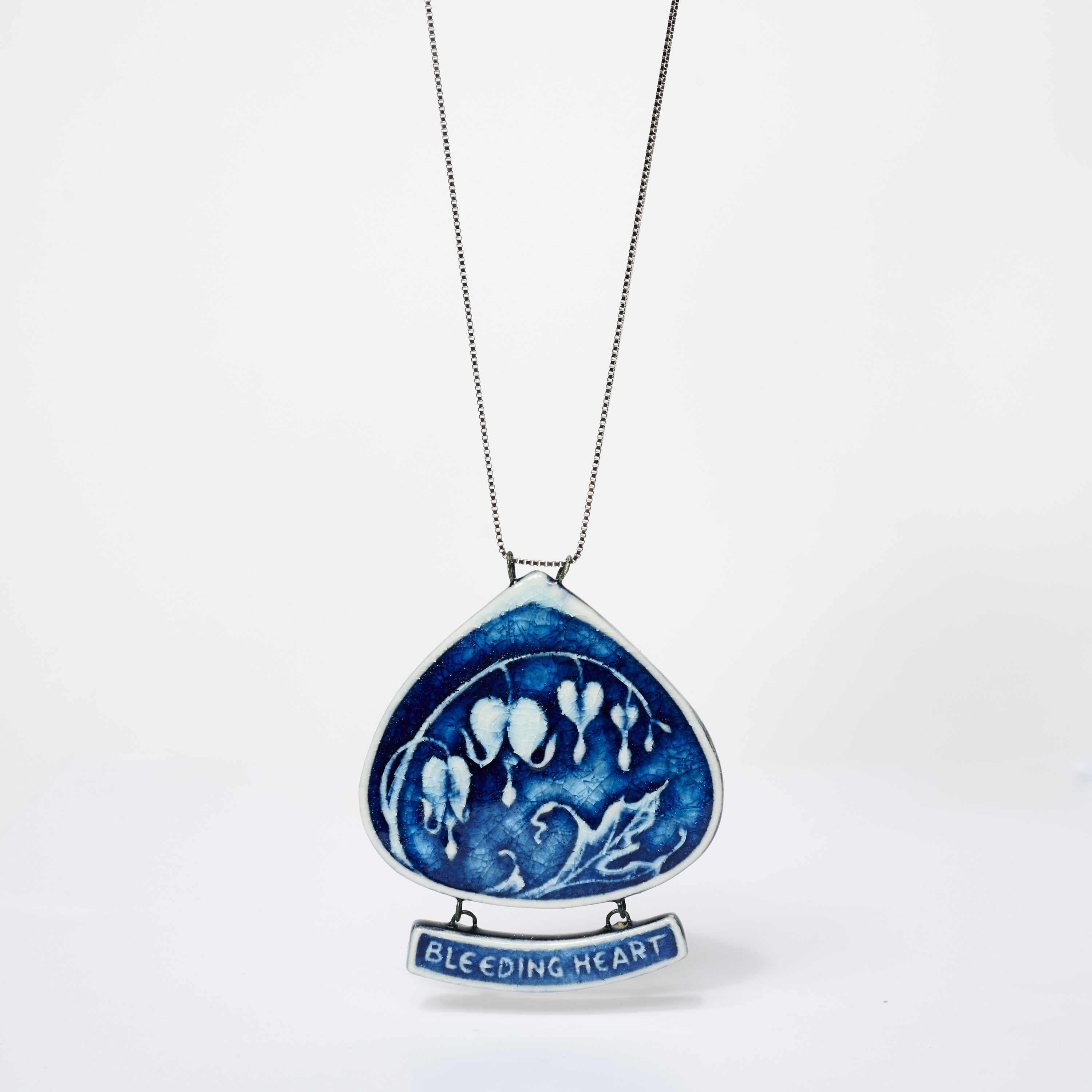 Blue ceramic pendant necklace with artistic design and silver chain.