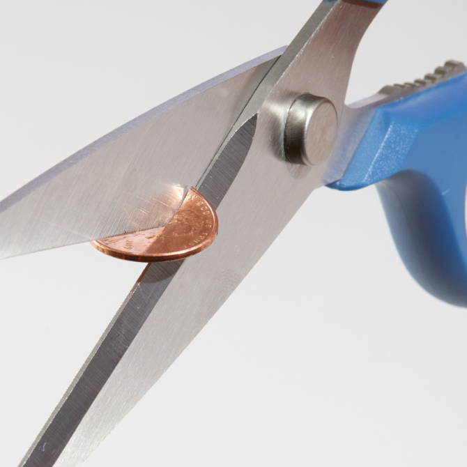 A set of Blue Misen Kitchen Shears cutting cleanly through a penny coin.