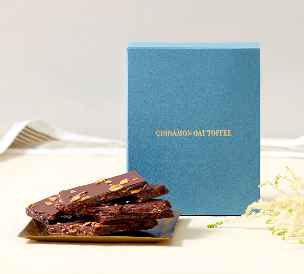 Blue box with golden text and chocolate treats on a plate.