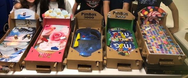 Five students who designed their own cardboard pinball machine as a STEM activity.