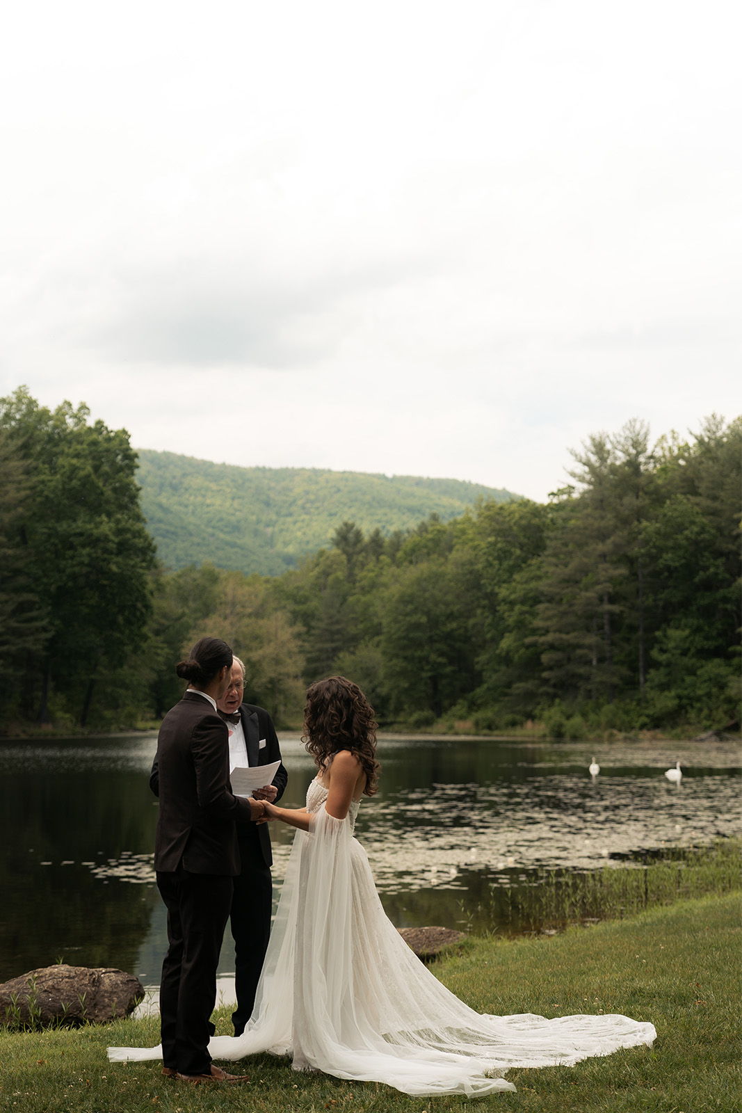 A couple exchanging vows by a serene lake in nature.