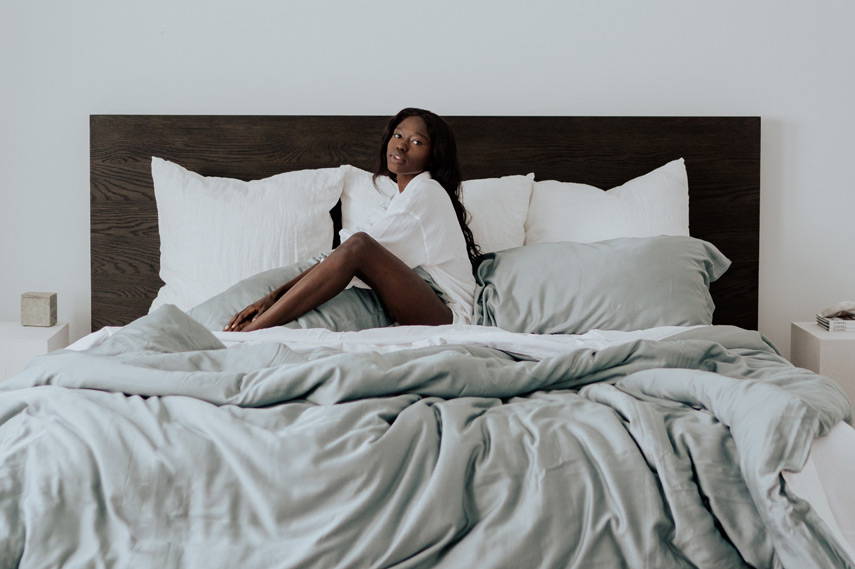 woman sitting on bed covered by a bamboo duvet cover
