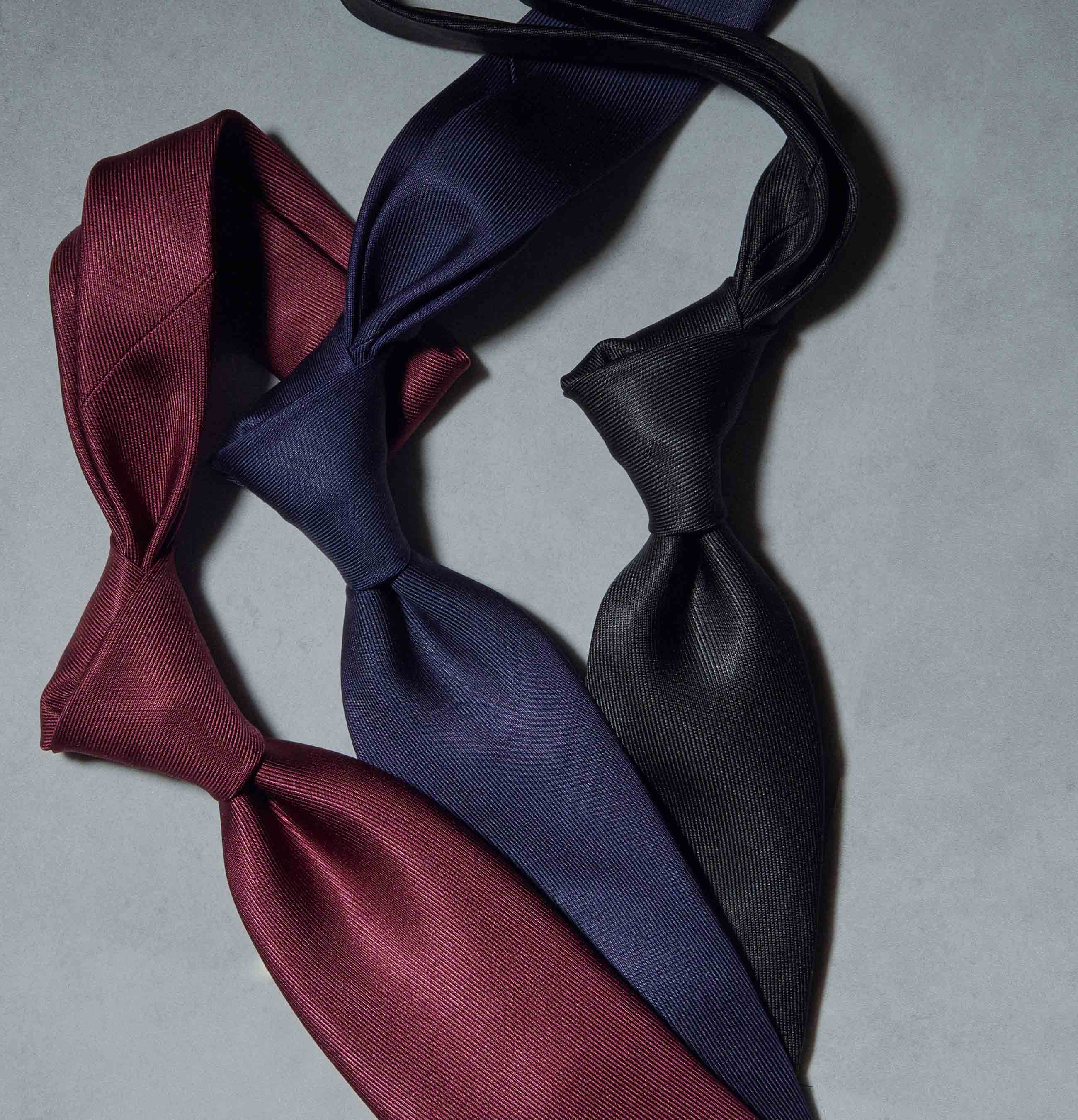 Three bow ties in burgundy, navy, and black on a gray background.