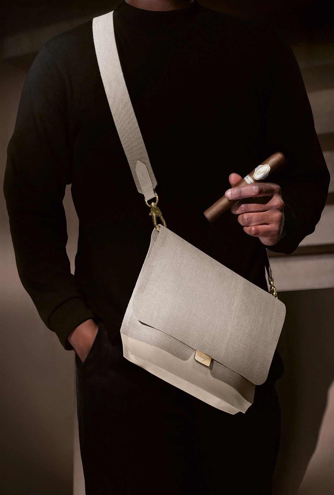 Ein Mann trägt den Travel Humidor mit Schulterriemen und hält eine Zigarre. 
